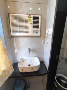 Un baño pequeño con lavabo y ventana. en Divine Fine Dine, en Kalyan