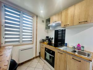 a kitchen with wooden cabinets and a sink and a stove at La Grange in Carentan