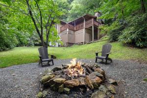 two chairs sitting around a fire pit in a yard at The Elk's Apple Grove, Upper Suite, Real Log Cabin in Maggie Valley