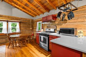 a kitchen with a stove and a table with chairs at The Elk's Apple Grove, Upper Suite, Real Log Cabin in Maggie Valley