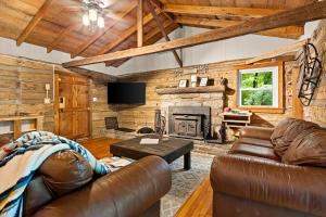 a living room with leather furniture and a fireplace at The Elk's Apple Grove, Upper Suite, Real Log Cabin in Maggie Valley