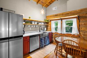 a kitchen with a stainless steel refrigerator and a table at The Elk's Apple Grove, Upper Suite, Real Log Cabin in Maggie Valley