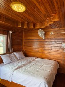 Una cama en una habitación de madera con ventilador. en วิมานหมอก ภูทับเบิก, en Ban Maeo Thap Boek