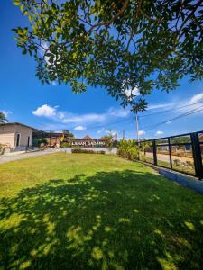 a green lawn with a tree in the foreground at Laman Gadang in Johol