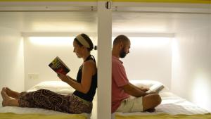 a man and woman sitting on a bed reading books at Ringo's Foyer in Melaka