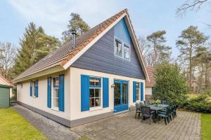 a house with blue windows and a patio at Zandduin Wellness Villa | 10 personen in Hooghalen