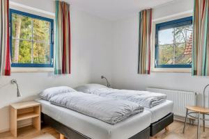 two beds in a room with two windows at Zandduin Wellness Villa | 10 personen in Hooghalen +25 photos
