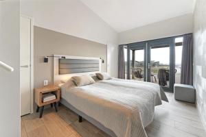 a white bedroom with a large bed and a window at Seaside Panorama Villa 6p - Direct aan de Baai - Villa 37 in Ouddorp