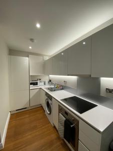 a kitchen with white cabinets and a washer at Cavendish Apartments in High Wycombe