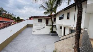 a balcony of a white building with a palm tree at Pousada Cahê in Ilhabela