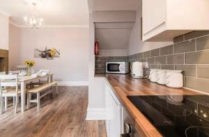 Una cocina con mesa de comedor y una cocina con gabinetes blancos. en Carnarvon Stays - 2 bed home, en Preston
