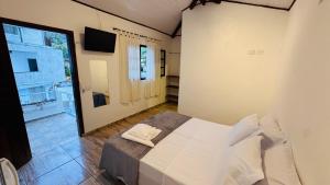 a bedroom with a bed in a room with a television at Pousada Cahê in Ilhabela