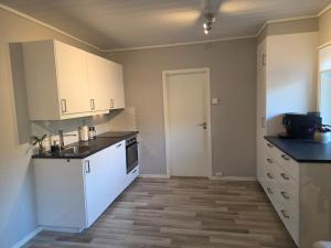 eine leere Küche mit weißen Schränken und einer Tür in der Unterkunft Apartment, Fosnavåg city center in Fosnavåg