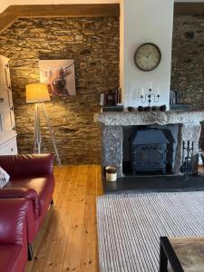 a living room with a stone fireplace with a clock at Tregolls Farm Cottages in Wadebridge