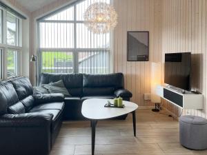 a living room with a black leather couch and a table at 8 person holiday home in Roslev-By Traum in Roslev +21 photos