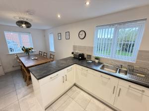 - une cuisine avec des placards blancs, un évier et une table dans l'établissement Cayton Bay Cottage, à Cayton