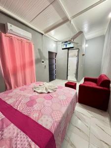 Un dormitorio con una cama rosa y una silla roja. en Hospedaje Ñande Roga, en Asunción