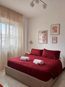 a bedroom with a red bed with two towels on it at Be Your Home - Cruise Stop Guest House in Civitavecchia