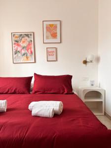a red bed with two towels on top of it at Be Your Home - Cruise Stop Guest House in Civitavecchia