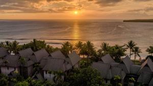 a sunset over the ocean with palm trees and houses at InterContinental Fiji Golf Resort & Spa by IHG in Natadola