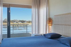 ein Schlafzimmer mit einem blauen Bett und einem großen Fenster in der Unterkunft Luxury Waterfront Retreat 4p - Comfort & Panoramisch Uitzicht - Villa 13 in Ouddorp