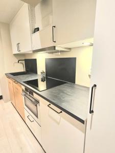 a kitchen with white cabinets and a black counter top at Fin 3-roms leilighet i Harstad sentrum in Harstad
