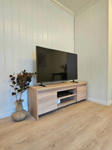 a flat screen tv sitting on top of a wooden entertainment center at Fin 3-roms leilighet i Harstad sentrum in Harstad