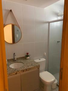 een badkamer met een toilet, een wastafel en een spiegel bij Village 2 suítes beira mar Itacimirim in Camaçari