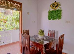 a dining room table with chairs and a plant on the wall at Linu Villa in Hikkaduwa