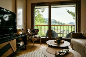 un salon avec une télévision et une grande fenêtre dans l'établissement Les Chalets de L'Aiguille C003, au Chinaillon