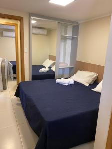 een slaapkamer met twee bedden en een spiegel bij Village 2 suítes beira mar Itacimirim in Camaçari +12 foto's