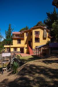 a large yellow house with a staircase in front of it at La Parada 