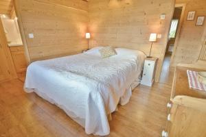 a bedroom with a white bed in a wooden room at Chalet Les Sonnailles du Mont in Le Grand-Bornand