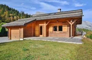 a large wooden building with a deck in the grass at Chalet Les Sonnailles du Mont in Le Grand-Bornand