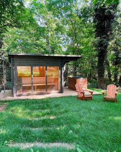 Ein Pavillon mit zwei Stühlen und einer Bank im Gras in der Unterkunft Maison de Reve avec Sauna en Pleine Foret in Le Vaudoué