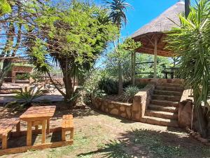 a garden with a gazebo with stairs and a table at Buck Hill Bush Lodge in Maanhaarrand