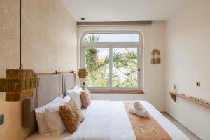 a bedroom with a large white bed with a window at The Shalak Villa Bali in Denpasar
