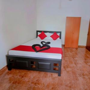 a bedroom with a bed with red and black pillows at Linu Villa in Hikkaduwa