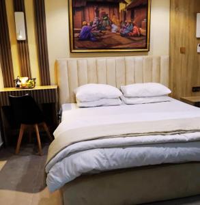 a bedroom with a bed with a painting on the wall at Rare Luxury 2bed guest house with private garden close to airport in Magodo