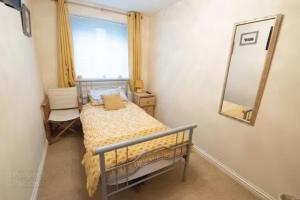 ein kleines Schlafzimmer mit einem Bett und einem Spiegel in der Unterkunft Portstewart promenade apartment with sea views in Portstewart