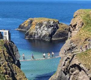 eine Gruppe von Menschen überquert eine Hängebrücke über den Ozean in der Unterkunft Portstewart promenade apartment with sea views in Portstewart + 20 Fotos