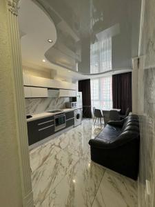 Il comprend un salon avec un canapé en cuir noir et une cuisine. dans l'établissement Квартира с евроремонтом, à Odessa