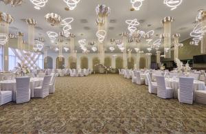 a banquet hall with white tables and chairs and chandeliers at AVO Hotel in Rîmnicu Sărat