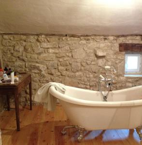 a bath tub in a room with a stone wall at La Grande Gueronie in Saint-Sernin