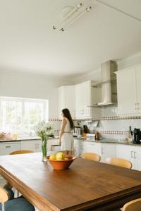 una mujer parada en una cocina con una mesa de madera en Casa do Sol Conscious Coliving, en Óbidos