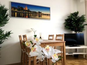 een eetkamer met een tafel en stoelen met witte bloemen bij Arcaden Apartment in Regensburg