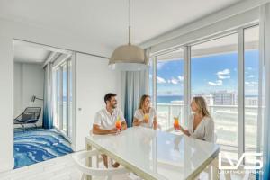 eine Gruppe von drei Personen sitzt mit Getränken an einem Tisch in der Unterkunft W FTL 1409 Beachfront Resort 2 Bedroom & 2 Bathroom Condo in Fort Lauderdale
