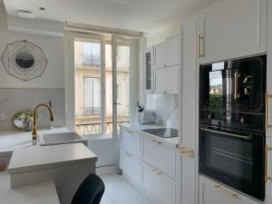 a kitchen with white cabinets and a black appliance at Appartement Vu Rhône - Vienne Centre in Vienne