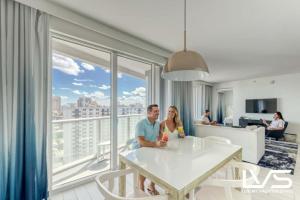 Ein Mann und eine Frau sitzen an einem Tisch im Wohnzimmer in der Unterkunft W Hotel Ftl Beach 1509 Oceanview 2Bed 2Bath Condo Resort in Fort Lauderdale