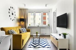 ein Wohnzimmer mit einem gelben Sofa und einem Fernseher in der Unterkunft Cozy Beachside Falla by Elite Apartments in Zaspa